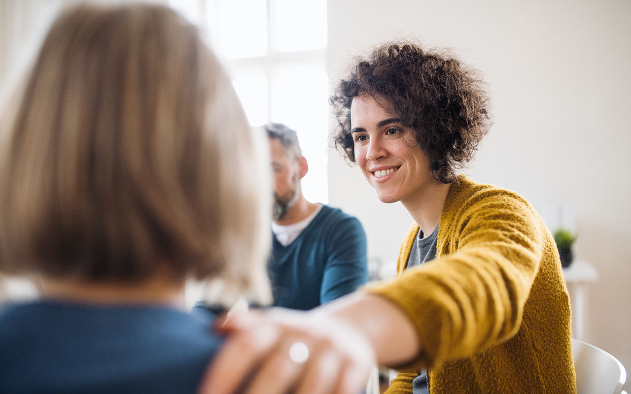 Therapist reaching out to client's shoulder and providing support.
