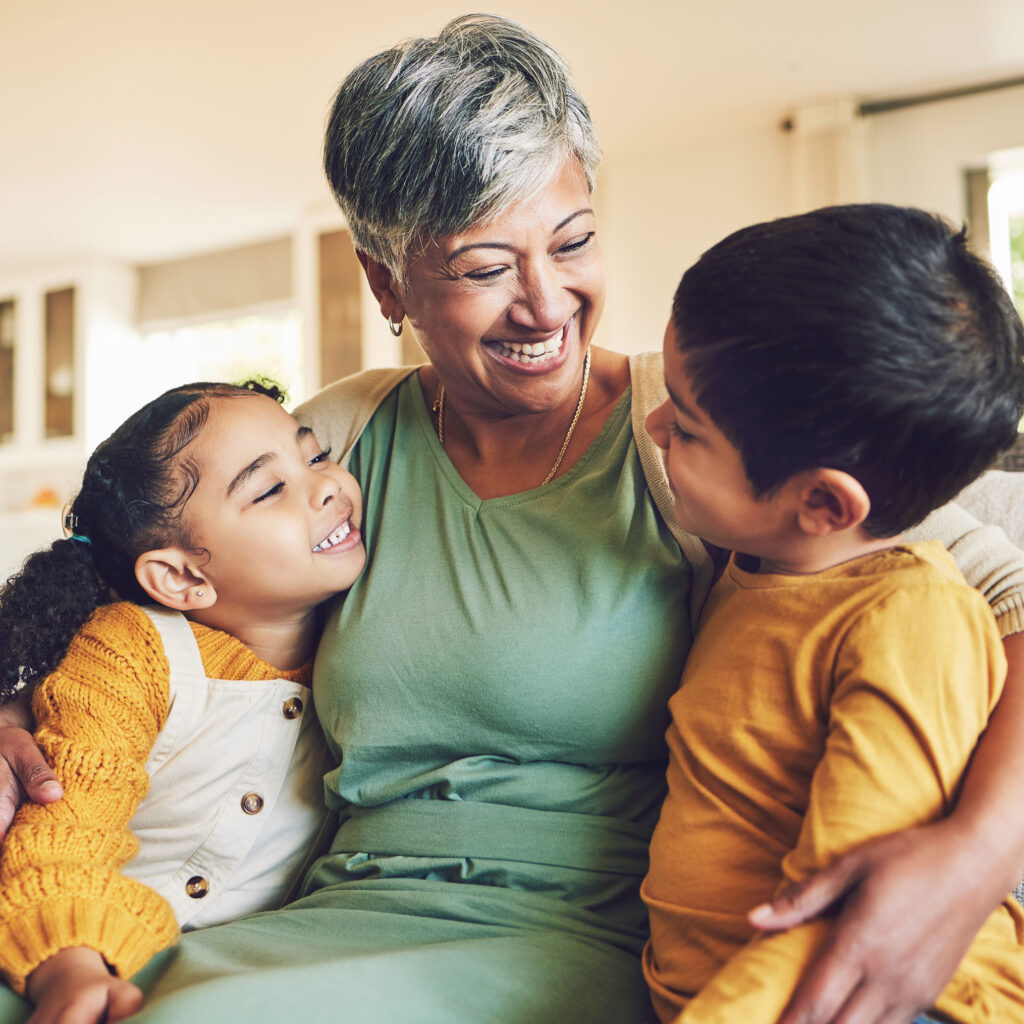 Grandmother and happy kids on a sofa with love enjoying quality bonding time together in family home. Thriving Communities